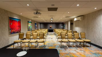 A conference room with rows of chairs, a podium, and a carpeted floor.