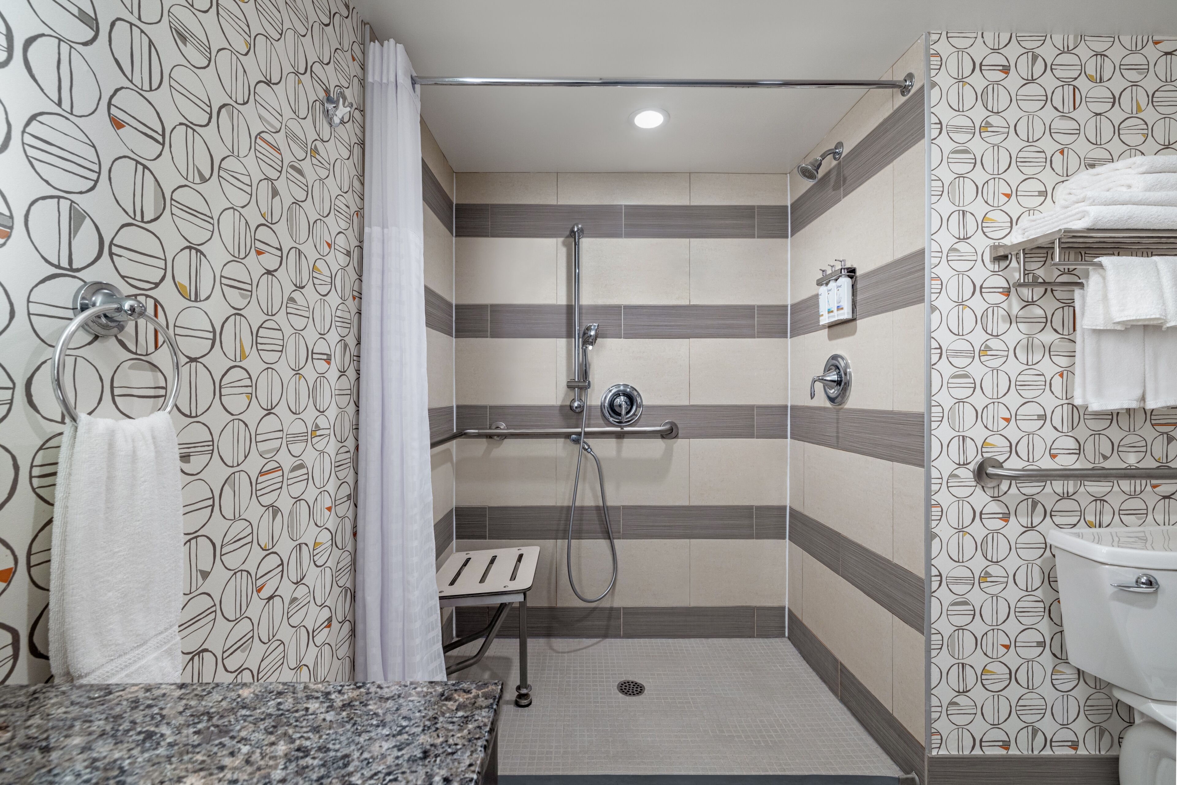 Une douche équipée d’un pommeau de douche à main, d’un porte-serviettes et d’une serviette.