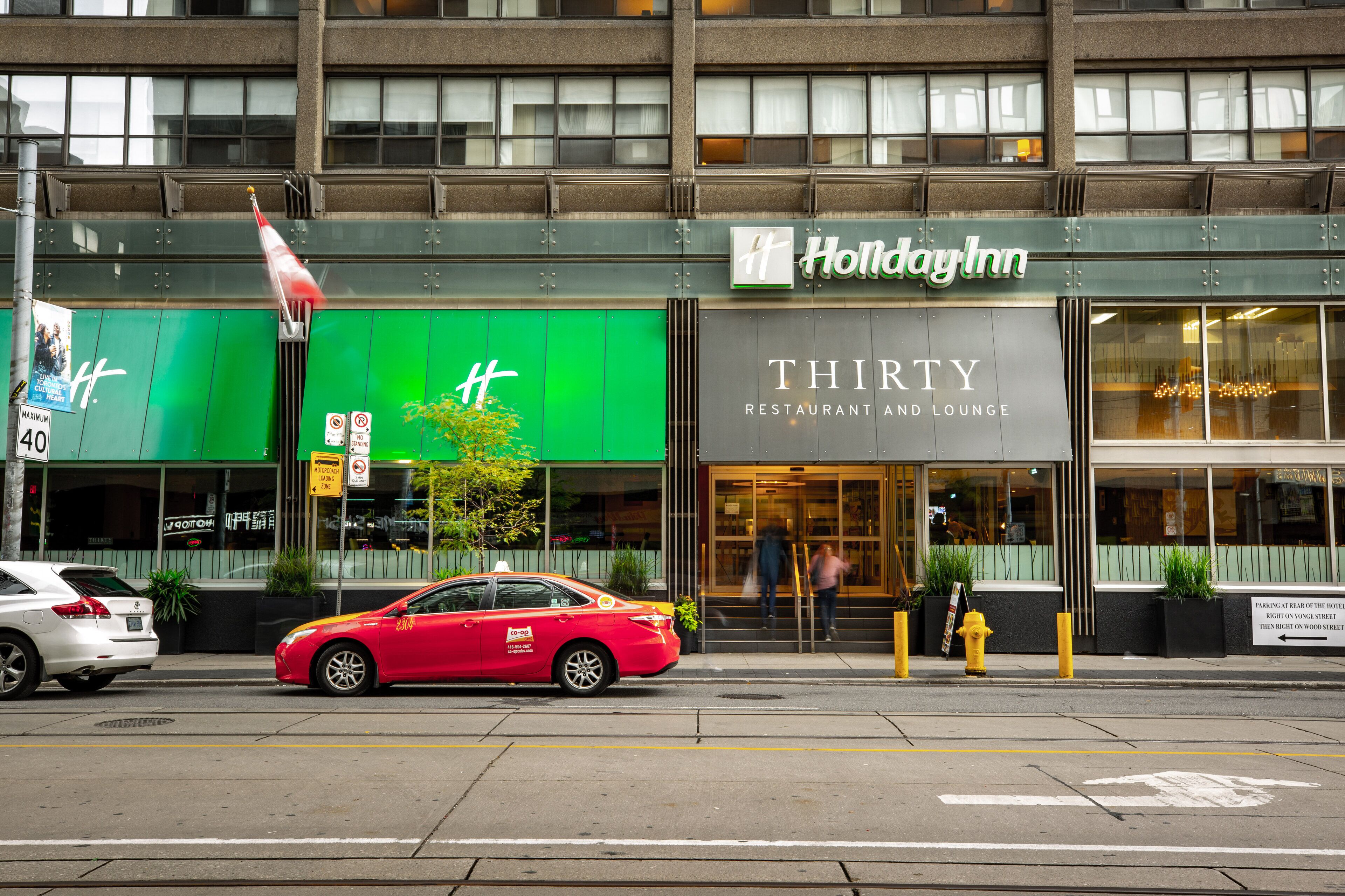 A building with a green sign for a restaurant and a sign for Holiday Inn.