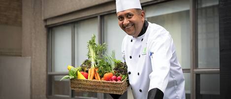 A chef holding a basket of fresh vegetables.