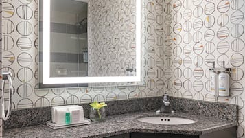 A bathroom with a granite countertop, a sink, a mirror, and a vanity area.