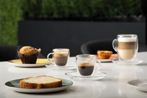 Een tafel met een muffin, twee kopjes koffie en een plakje brood.