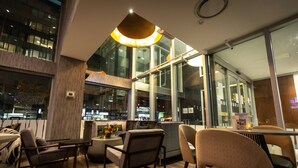 Un interior modern amb disposició de seients, grans finestres i una làmpada central.