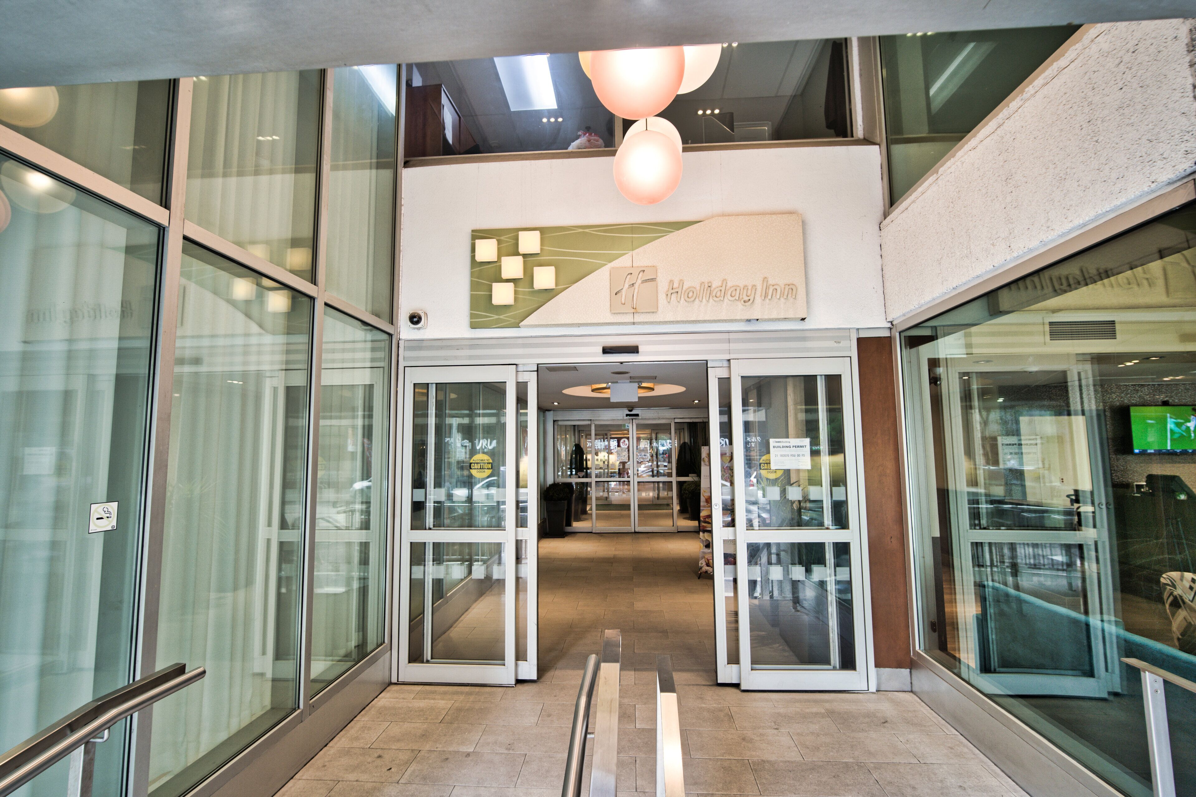 L’entrée d’un hôtel Holiday Inn, avec des portes vitrées, une rampe et une enseigne au-dessus des portes.