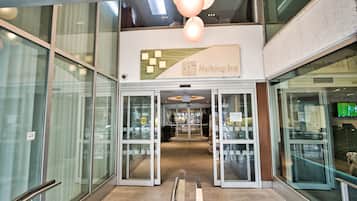 L’entrée d’un hôtel Holiday Inn, avec des portes vitrées, une rampe et une enseigne au-dessus des portes.