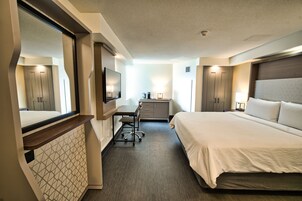Een hotelkamer met een bed, bureau, stoel en kledingkast.