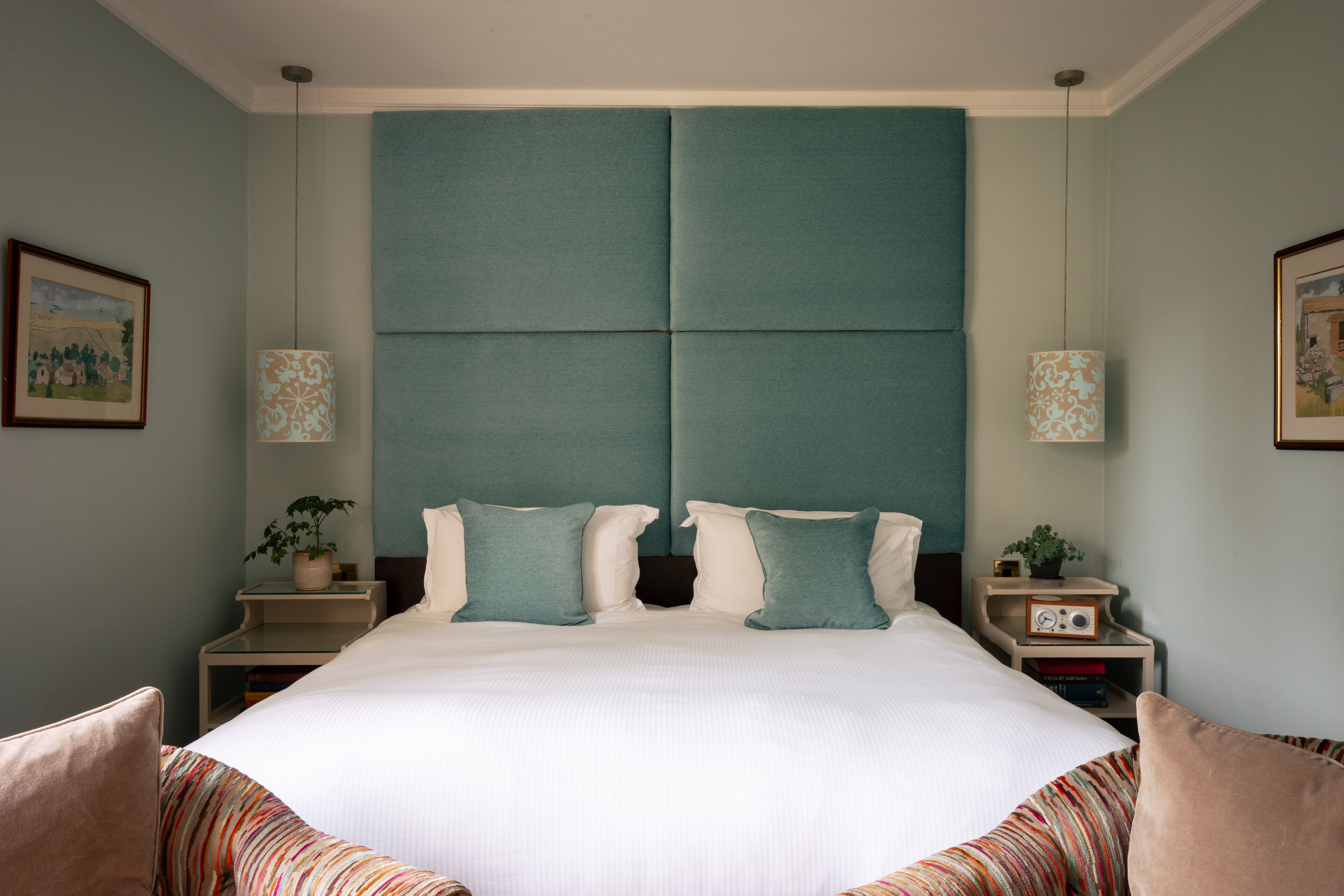 A neatly arranged bedroom with a large bed, two bedside tables, and a headboard.