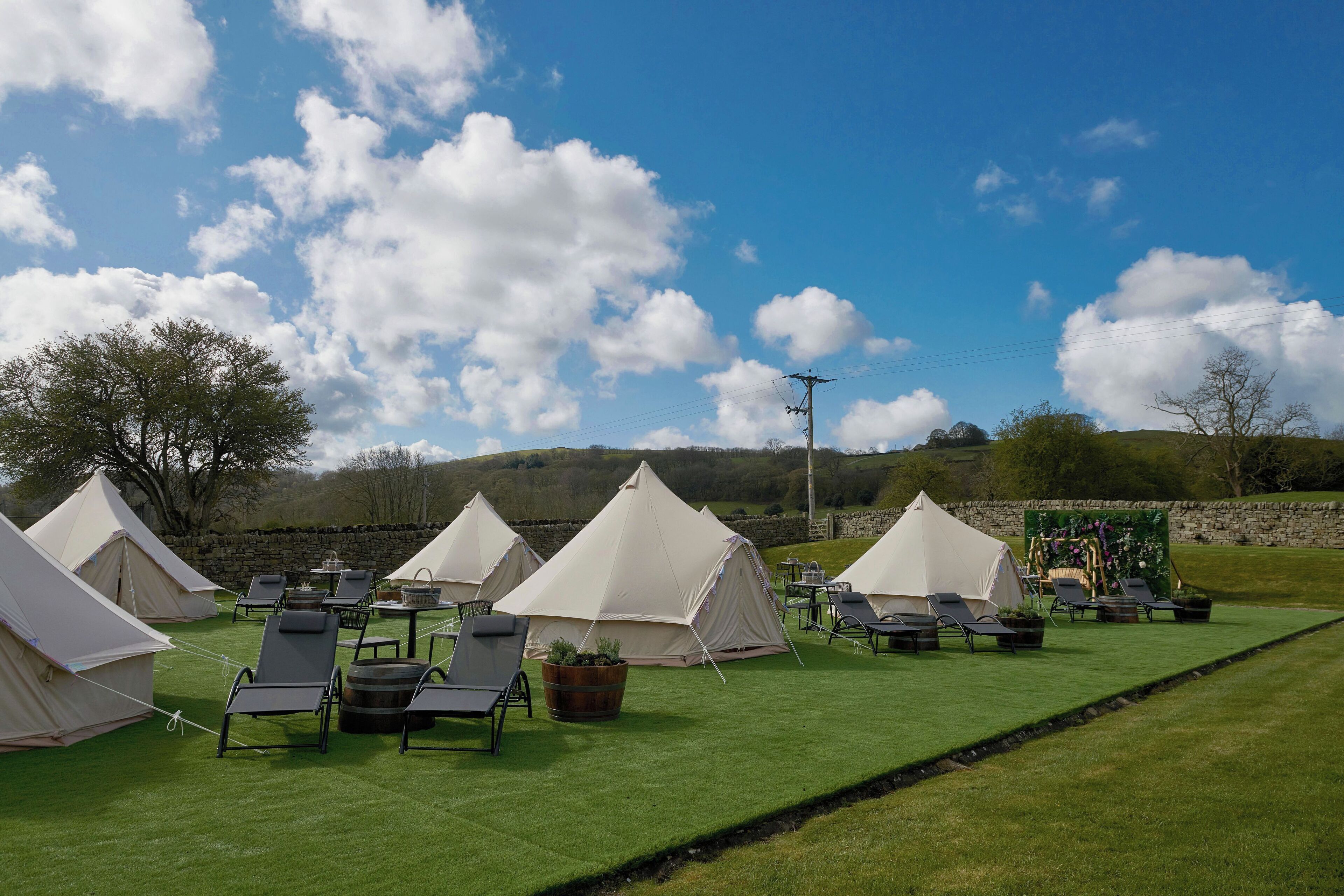 A campsite with multiple tents and lounge chairs arranged on a grassy area.