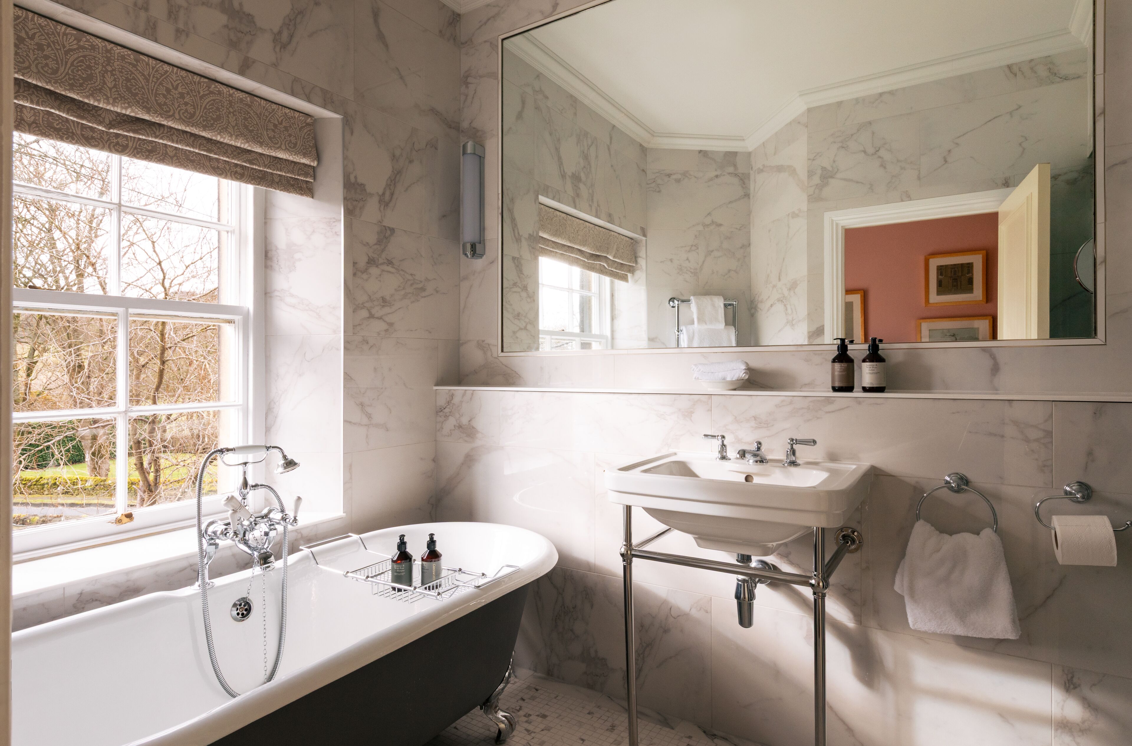 A bathroom with a freestanding bathtub, a sink, and a large mirror.