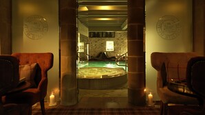 A spa area with a hot tub, stone walls, and two wooden chairs. - The Devonshire Arms Hotel (Skipton)