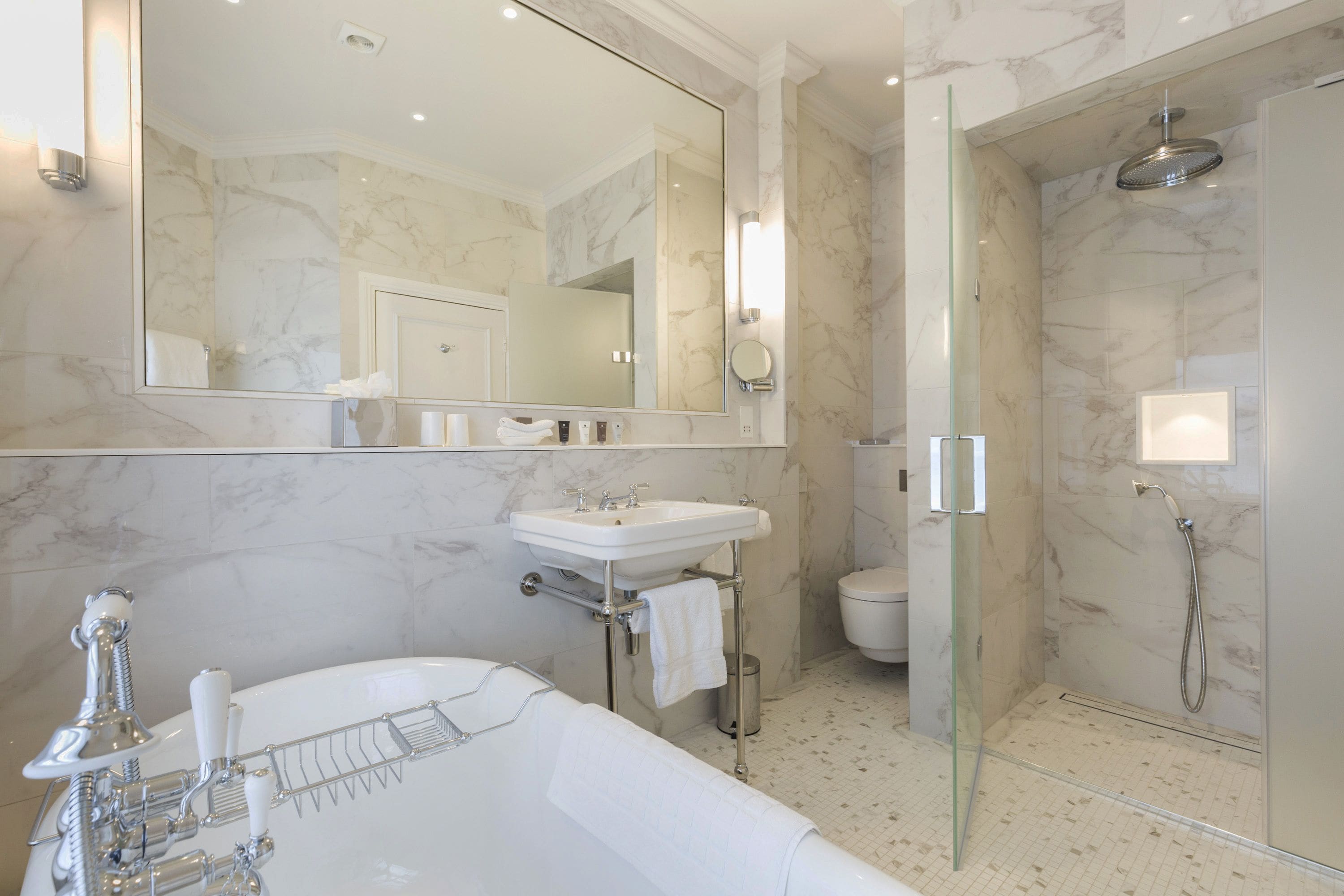 Ein modernes Badezimmer mit großem Spiegel, einer Badewanne, einer Dusche und einem WC.