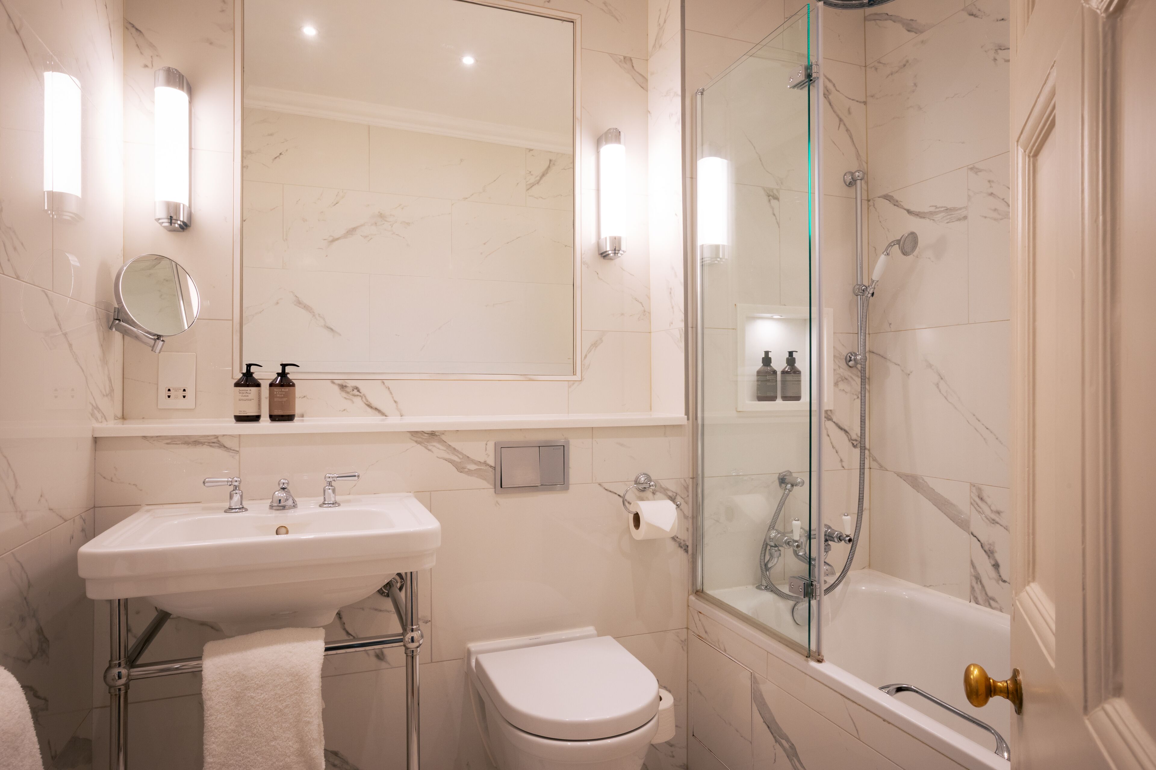 A bathroom with a marble sink, toilet, and glass-enclosed shower.