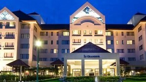 A multi-story hotel with a central atrium and a sign reading "Le Grand Hôtel". - Le Grandeur Balikpapan (Balikpapan)