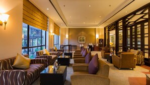 A spacious lobby with multiple seating areas, a large window with a view, and a bookshelf with various items. - Le Grandeur Balikpapan (Balikpapan)