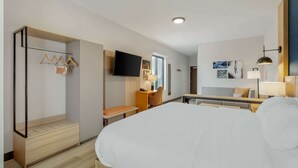 Una habitación de hotel moderna con cama, escritorio, silla y televisor.
