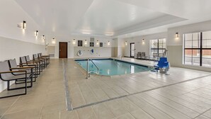 A swimming pool area with a tiled floor, benches, and a pool ladder.