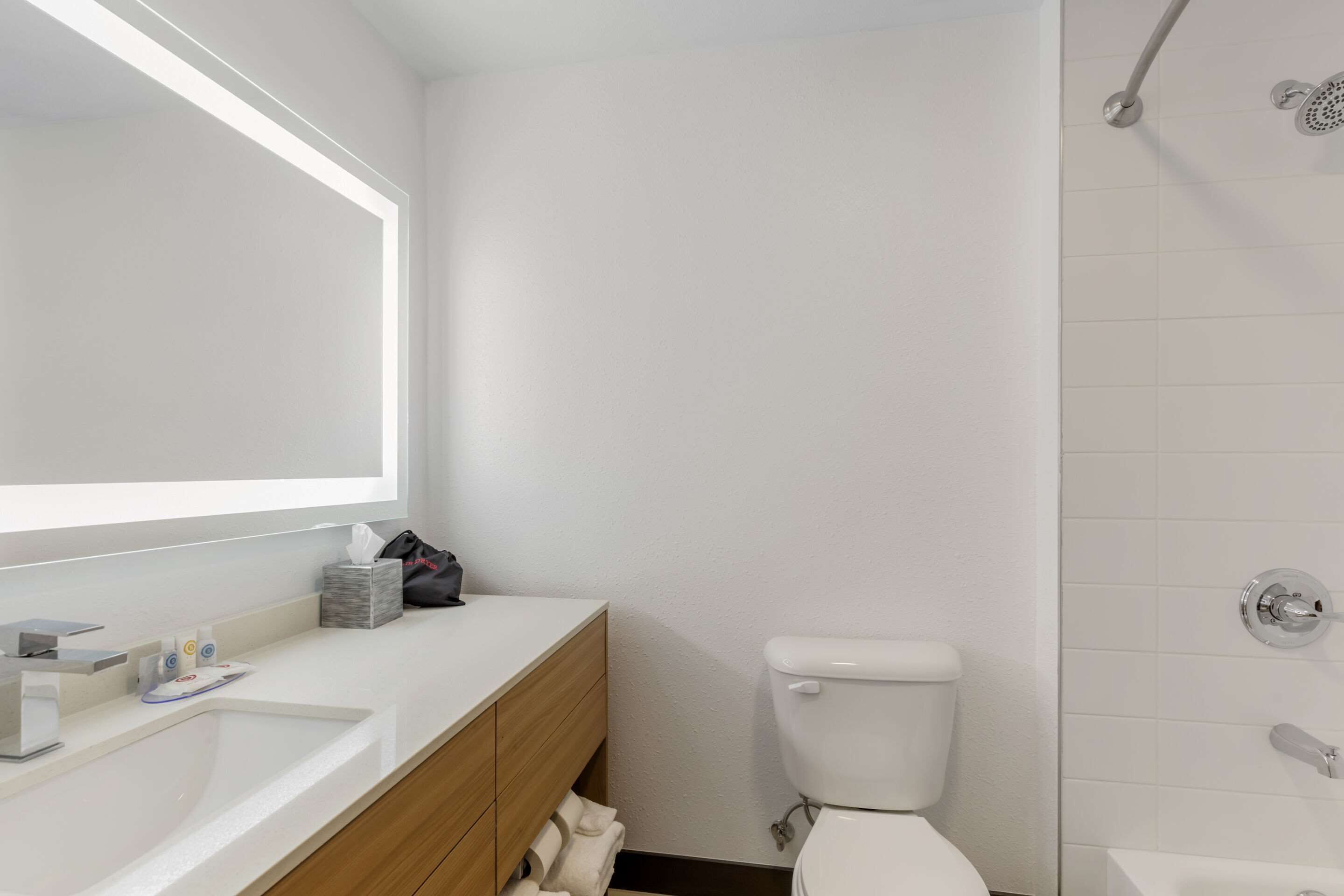 A modern bathroom with a white sink, vanity, and toilet.