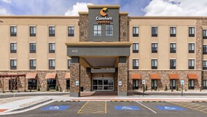 Un hotel Comfort Suites con un diseño moderno, que presenta fachada de piedra, varias ventanas y una entrada despejada.