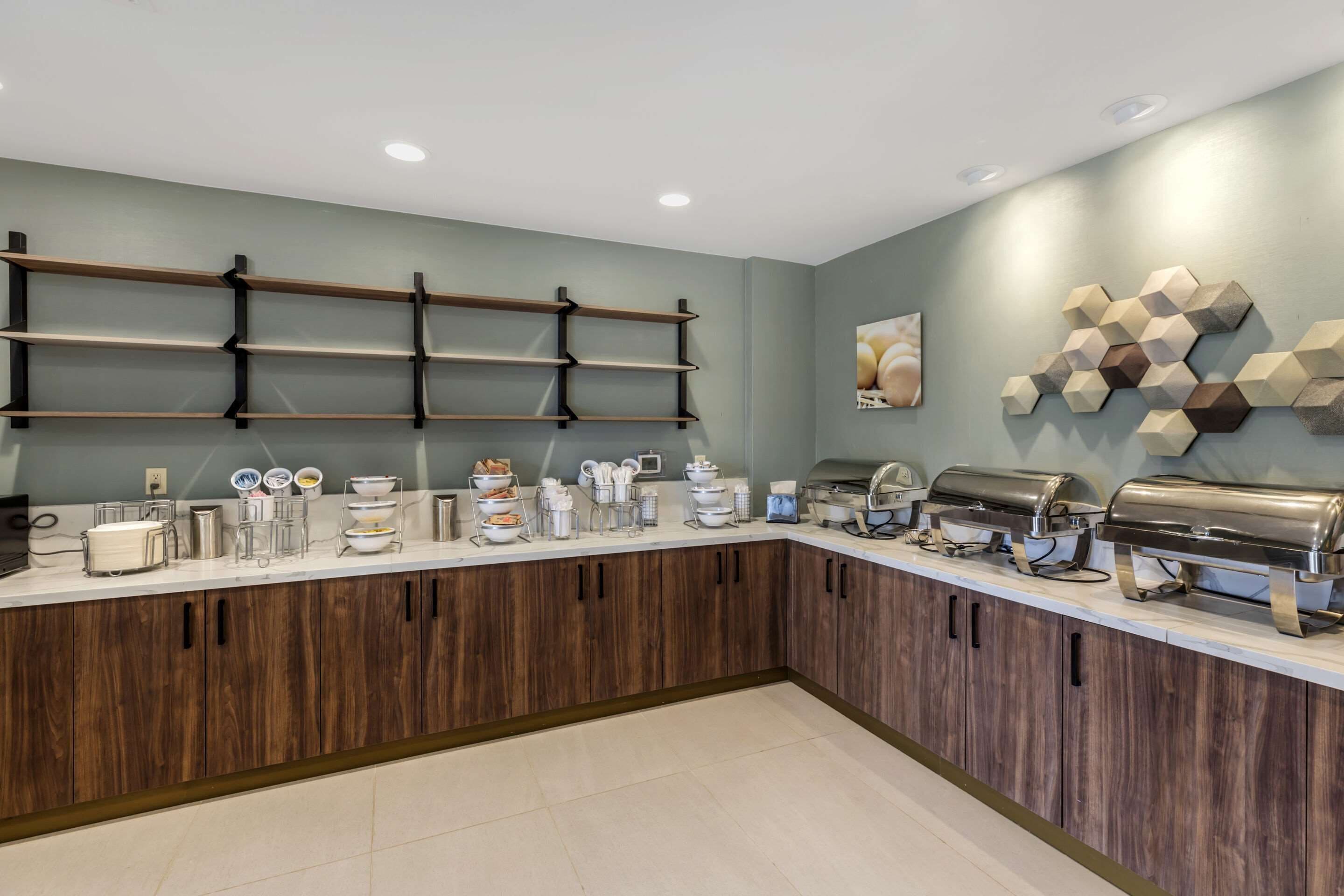 A modern kitchen with wooden cabinets, a white countertop, and various kitchen appliances.