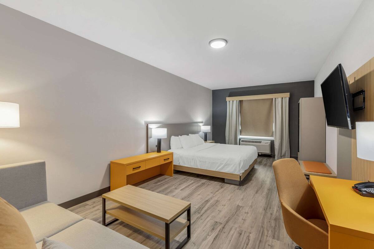 Une chambre d’hôtel comprenant un lit, des tables de chevet, un bureau, une chaise et un téléviseur.