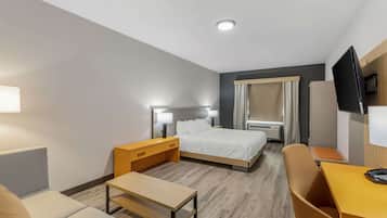 A hotel room with a bed, bedside tables, a desk, a chair, and a TV.