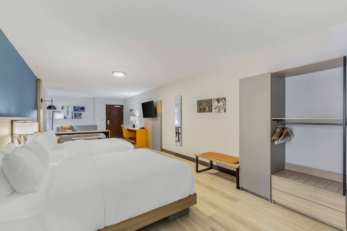 Une chambre d’hôtel moderne équipée d’un grand lit, d’un bureau, d’une chaise, d’un banc et d’une armoire.