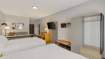 A hotel room with two beds, a desk, a chair, a TV, and a wardrobe.