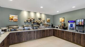 A modern breakfast bar with a wooden counter, various food dispensers, and wall art.