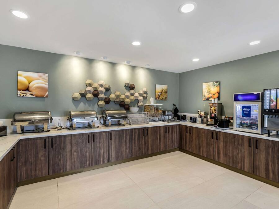 A modern breakfast bar with a wooden counter, various food dispensers, and wall art.