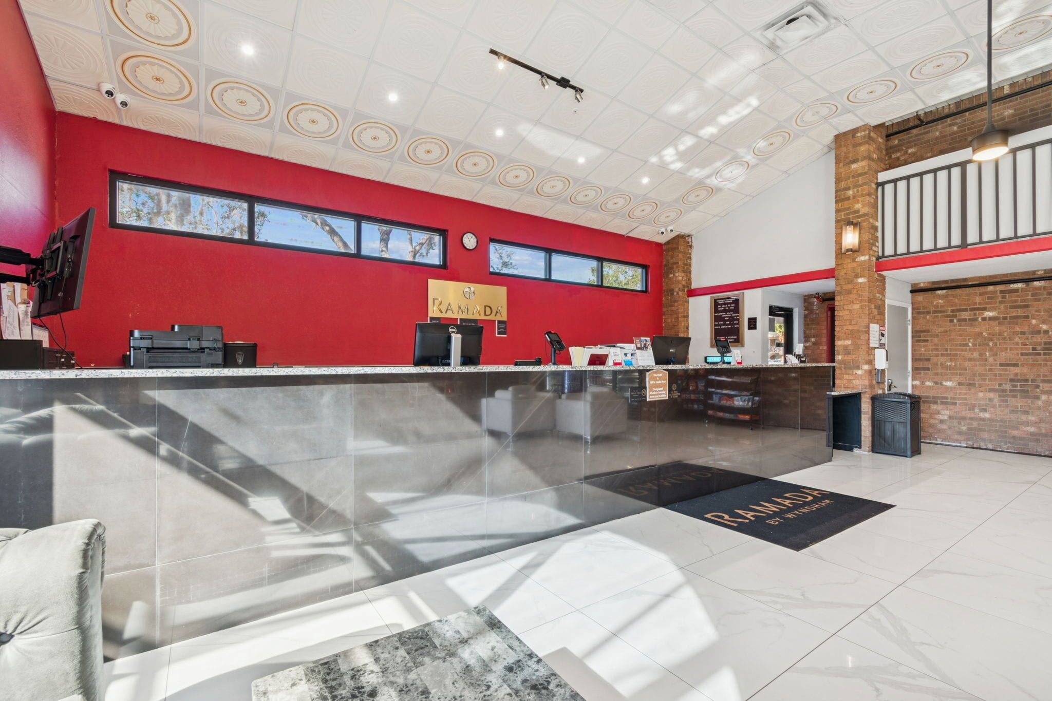 A reception area with a red wall, a black reception desk, and a black and white floor mat.