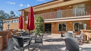 An outdoor patio area with brick walls, outdoor seating, and a Christmas tree. - Ramada by Wyndham Temple Terrace/Tampa North (Tampa)