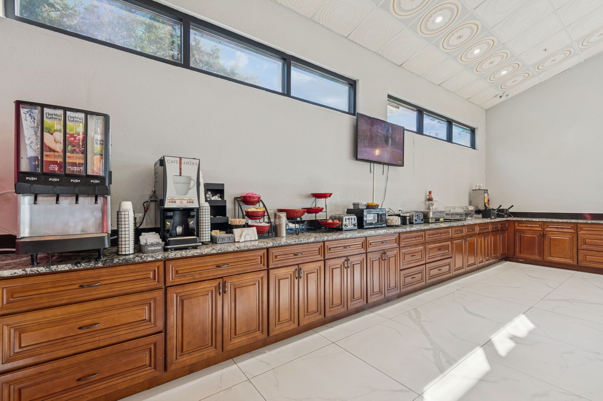 Een ruime keuken met houten kastjes, een koffiehoek en een flatscreen tv aan de muur.