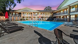 A hotel with a swimming pool, outdoor seating, and a two-story building with balconies. - Ramada by Wyndham Temple Terrace/Tampa North (Tampa)