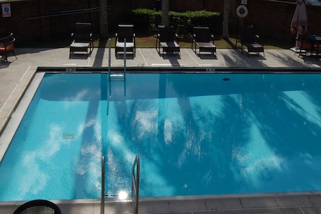 Una piscina al aire libre, sombrillas, sillones reclinables de piscina