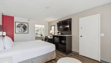 A hotel room with a bed, a desk with a TV, a microwave, and a wardrobe.