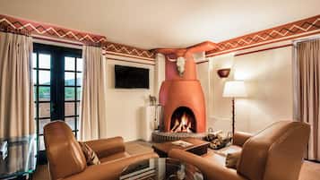 Ein Wohnzimmer mit Ledersofas, einem Glastisch, einem Kamin mit einer Stierkopf-Dekoration, einem Flachbildfernseher und einer Lampe.