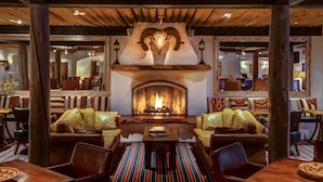 A cozy lounge area with a fireplace, leather sofas, and a wooden ceiling.