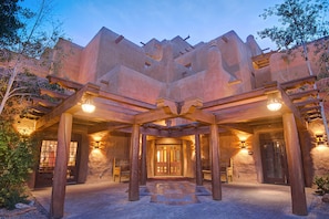 A building with a unique architectural style, featuring a central entrance with a wooden pergola and stone walls.