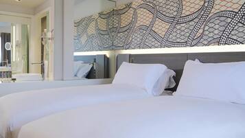 A modern hotel room with a large bed, a bathroom with a mirror, and a decorative wall pattern.