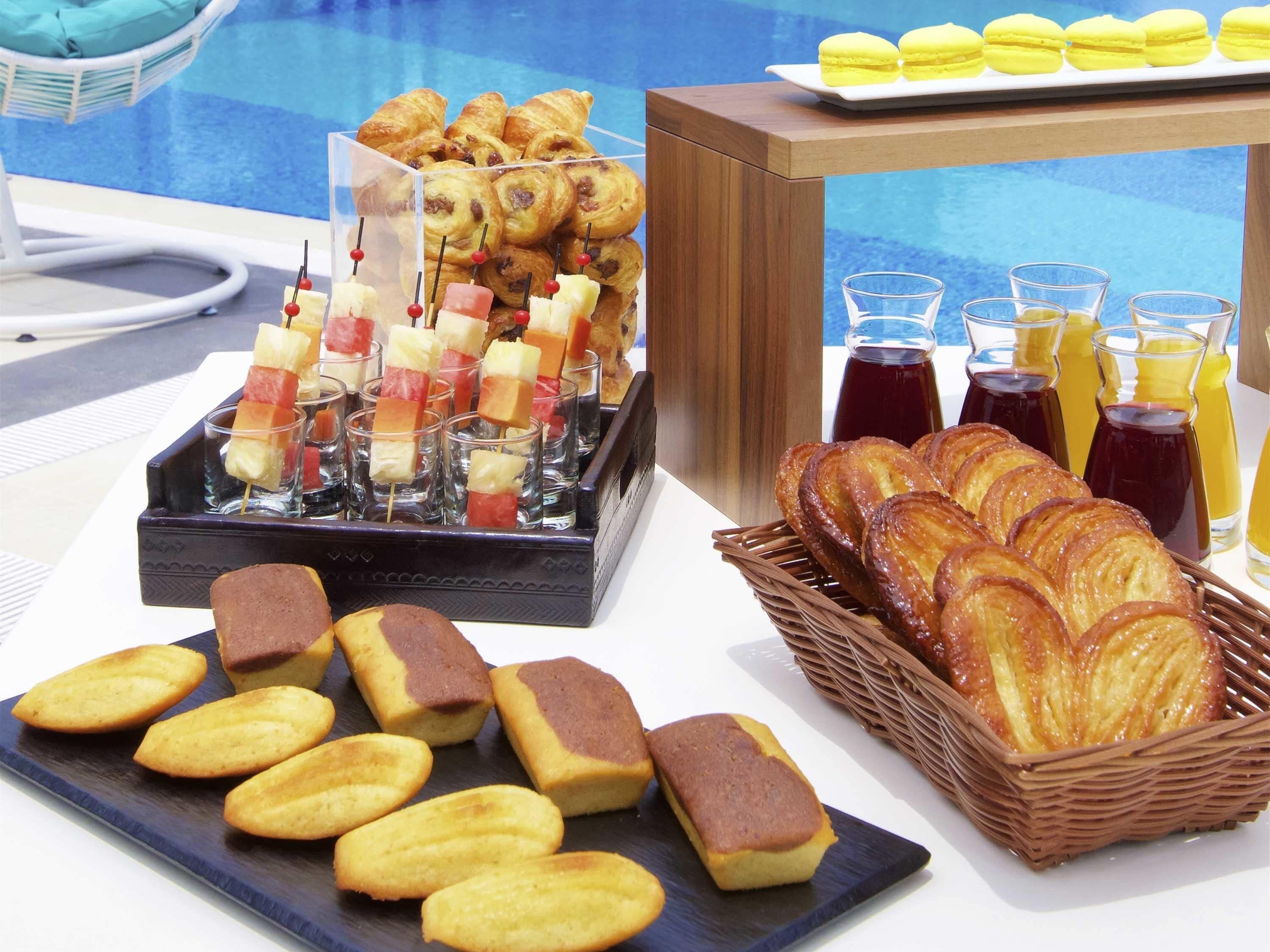 A buffet with pastries, fruit skewers, and beverages.