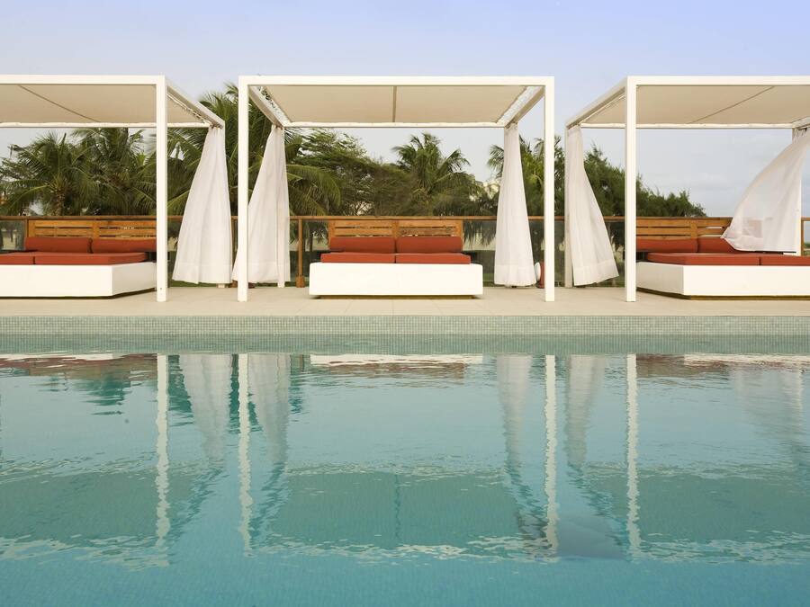 Una piscina al aire libre, sombrillas, sillones reclinables de piscina