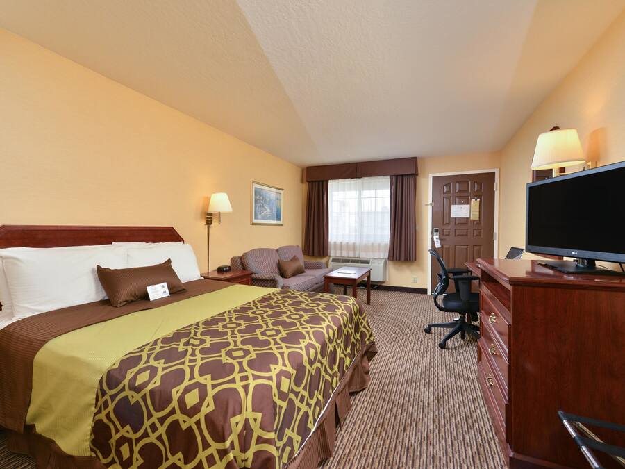 Una habitación de hotel con una cama grande, un escritorio, una silla, un televisor y una ventana con cortinas.