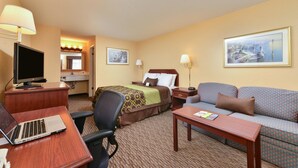 A hotel room with a bed, a sofa, a desk with a laptop, a TV, and two paintings on the wall. - Americas Best Value Inn San Jose Convention Center (San Jose)