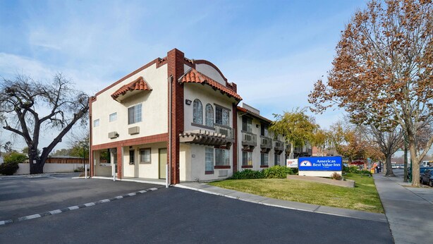 A two-story building with a red-tiled roof, a sign for 'Americas Best Value Inn', and a parking lot in front. - Americas Best Value Inn San Jose Convention Center (San Jose)