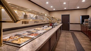 A buffet area with multiple food stations, a door, and a microwave in the background.