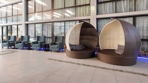A lobby with a row of blue armchairs and two large wicker bean bags with cushions. - Wingate by Wyndham Kansas City (Kansas City)