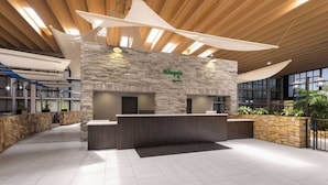 A reception area with a stone wall, a wooden ceiling, and a reception desk. - Wingate by Wyndham Kansas City (Kansas City)