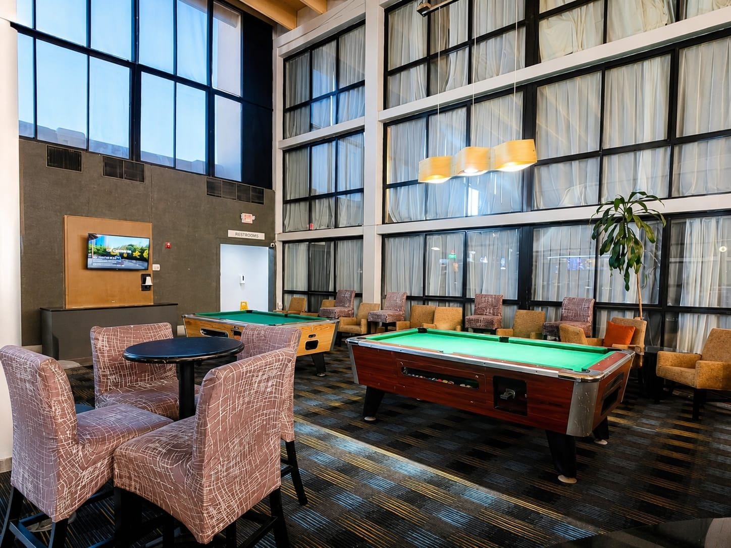 A pool table in a room with large windows, chairs, and a television.