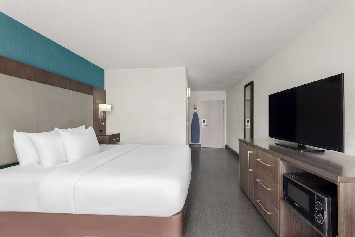 Ein Hotelzimmer mit einem großen Bett, einem Flachbildfernseher, einer Mikrowelle und einem Schminktisch.
