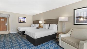 A hotel room with a bed, two bedside tables, a lamp, a couch, and a patterned carpet.